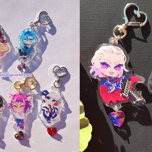 May include: A set of ten colorful anime character keychains with heart-shaped charms. The keychains are made of clear acrylic and feature different characters with various expressions and poses. The keychains are perfect for adding a touch of anime style to your bag, keys, or phone.