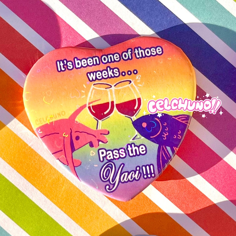 May include: A heart-shaped button with a rainbow background. It features two wine glasses clinking, a red lobster, a purple fish, and the text "It's been one of those weeks...  Celchuno!! Pass the Yaoi!!!"