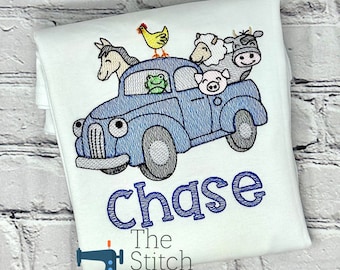 May include: White t-shirt with a blue embroidered design of a blue car carrying farm animals, including a horse, chicken, frog, sheep, pig, and cow. The name "chase" is embroidered in blue below the car. The Stitch Box logo is at the bottom.