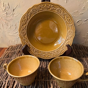 May include: A set of three brown ceramic bowls with an ornate design. The bowls are all the same size and shape, and they have a glossy finish.