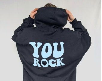Könnte beinhalten: Schwarzer Kapuzenpullover mit einem hellblauen Aufdruck auf der Rückseite, der "YOU ROCK" mit einem Herzsymbol sagt.