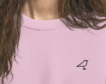 May include: A pale pink sweatshirt with a small black bird embroidered on the front.