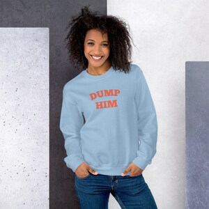 K&ouml;nnte beinhalten: Ein hellblauer Pullover mit dem Aufdruck "DUMP HIM" in Rot auf der Vorderseite.