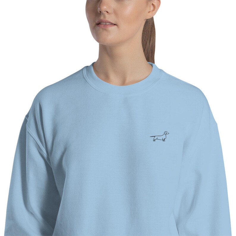 May include: A light blue sweatshirt with a small black dachshund outline embroidered on the front.