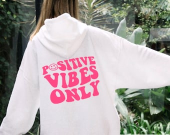 May include: White hoodie with a pink graphic that says "POSITIVE VIBES ONLY" with a smiley face in the "O" of "POSITIVE".