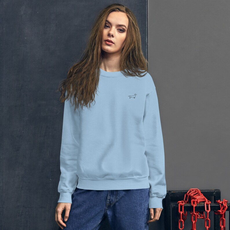 May include: A light blue sweatshirt with a small black dachshund outline embroidered on the left chest.