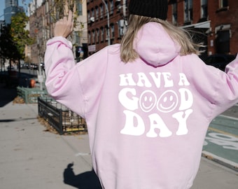 May include: Pink hoodie with a white graphic that says "Have a Good Day" with two smiley faces.