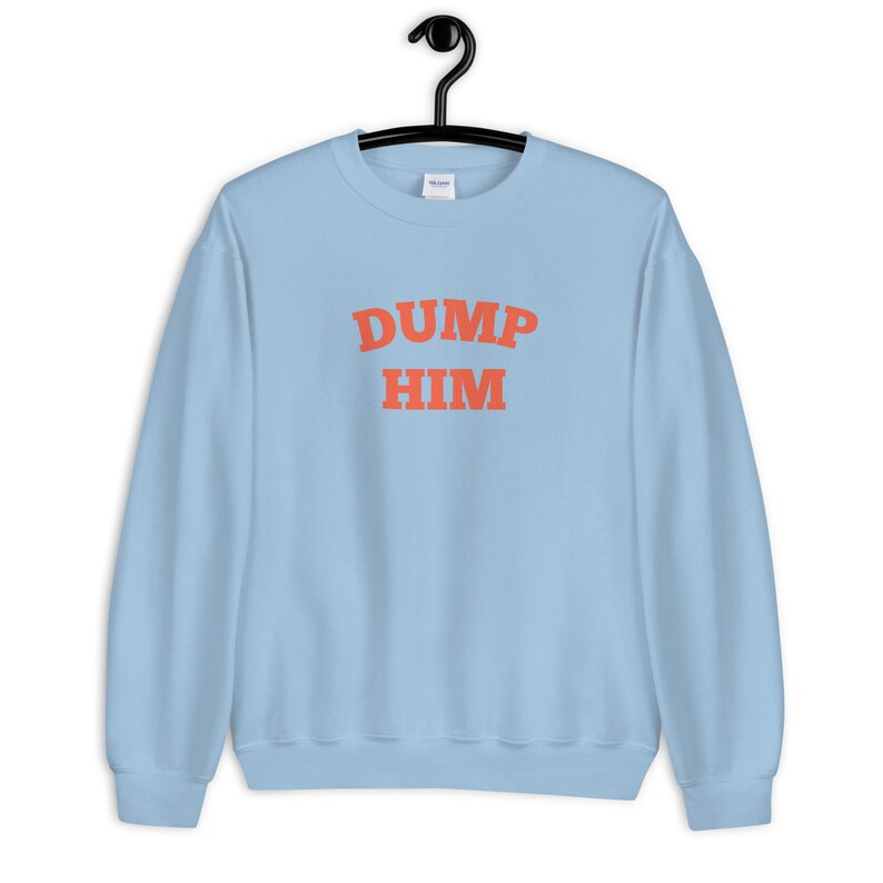 K&ouml;nnte beinhalten: Hellblauer Pullover mit dem Text "DUMP HIM" in Orange.