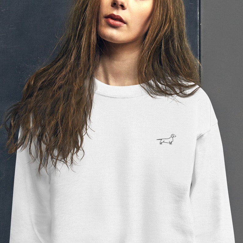 May include: White crew neck sweatshirt with a small black line drawing of a dachshund on the front.