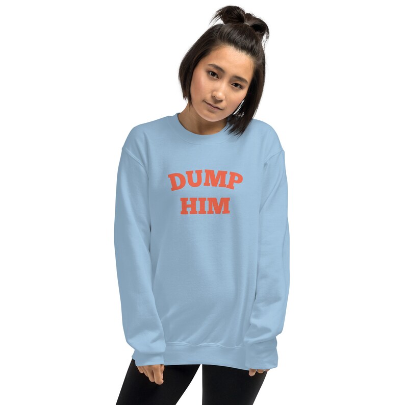 K&ouml;nnte beinhalten: Ein hellblauer Pullover mit dem Text "DUMP HIM" in Rot.