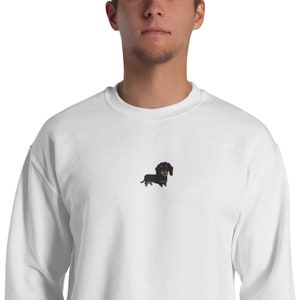 Op de afbeelding: Een wit sweatshirt met een zwarte en bruine teckel geborduurd op de voorkant.