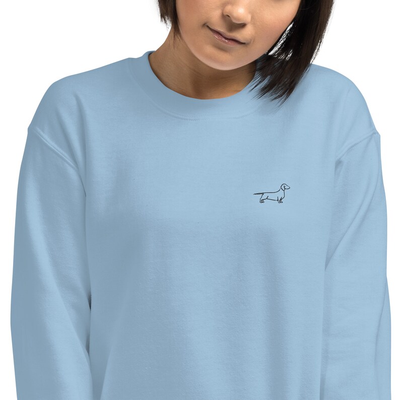 May include: A light blue sweatshirt with a simple black line drawing of a dachshund on the front.