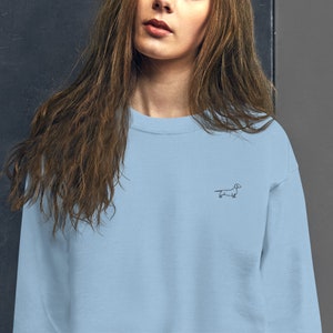 May include: A light blue sweatshirt with a small black dachshund silhouette embroidered on the front.