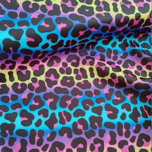 May include: A black and white leopard print fabric with a gradient of pink, blue and yellow.