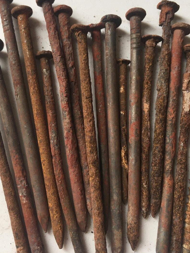 Group of old, rusty nails with varying lengths and sizes, showcasing their worn and weathered appearance. These nails are used in witchcraft for baneful magic, cursing, hexing, and powerful black magic spells