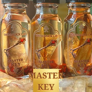 May include: Three small glass bottles filled with a golden liquid and a gold key charm. The bottles have labels that read "The Magick Lab" and "Master Key".
