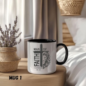 May include: White ceramic mug with a black interior and handle. The mug features the text "MAN OF FAITH" with a cross and a lion's head graphic. The text "1 Corinthians 16:13" is also printed on the mug. The mug is labeled "MUG 1".