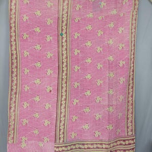 May include: A rectangular textile featuring a vibrant pink base with a repeating pattern of small yellow and white floral clusters. The fabric is adorned with thin, wavy white lines and includes vertical border panels with floral motifs.
