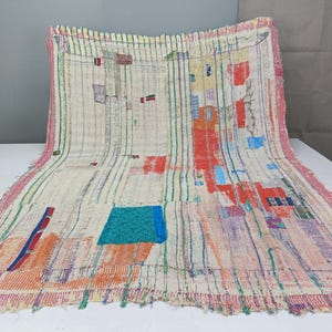 May include: A rectangular textile featuring a cream-colored base with vertical green stripes and various patches of red, orange, blue, and purple fabric. The edges are frayed, and the surface displays visible running stitch embroidery throughout the piece.