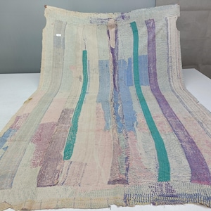 May include: A rectangular textile featuring a layered patchwork design with visible running stitch patterns. The fabric displays a color palette of off-white, light pink, teal, and purple vertical stripes and rectangular blocks throughout the surface.
