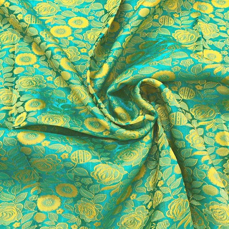 May include: A close-up of a teal fabric with a yellow floral pattern. The fabric is folded and draped, showing the texture and detail of the design.