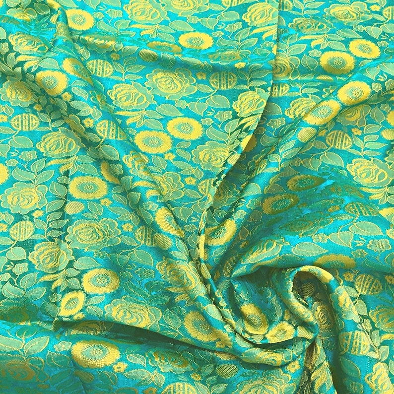 May include: Teal fabric with a yellow floral pattern. The fabric is woven with a raised texture, giving it a three-dimensional look.