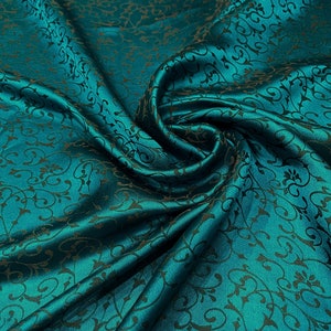 May include: Teal fabric with a black floral pattern. The fabric is smooth and silky.
