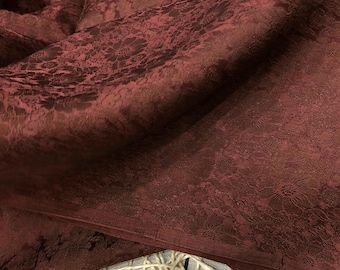 May include: Close-up of a burgundy fabric with a subtle floral pattern. The fabric has a soft, textured surface.