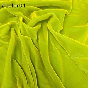May include: A close-up of a bright green velvet fabric. The fabric is soft and smooth, with a subtle sheen. It is ideal for a variety of sewing projects, such as dresses, skirts, and jackets.