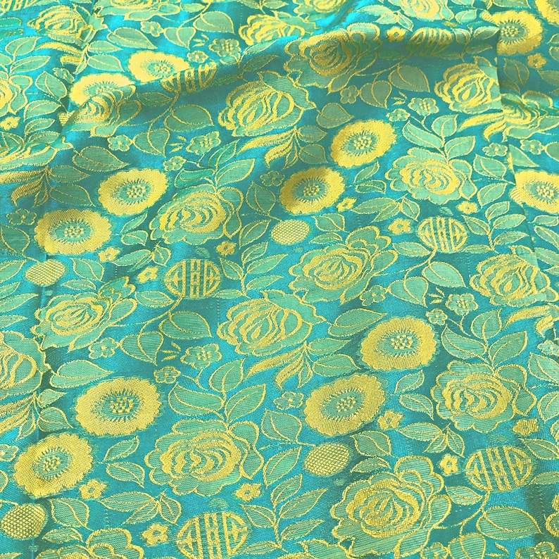 May include: Teal fabric with a yellow floral pattern. The fabric has a textured, woven look.