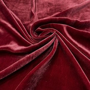 May include: Close-up of a deep red velvet fabric with soft folds and a smooth texture.
