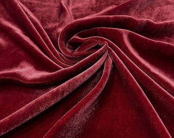 May include: Close-up of a deep red velvet fabric with soft folds and a smooth texture.