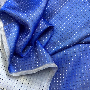 May include: Blue fabric with a white polka dot pattern. The fabric is sheer and has a slight sheen.