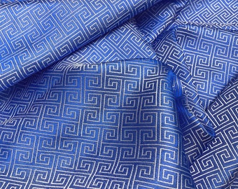 May include: Blue fabric with a white geometric pattern. The fabric is folded and draped, showing the pattern from different angles.