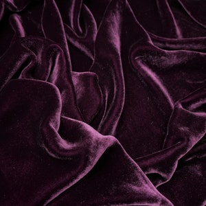 Könnte beinhalten: Nahaufnahme eines tiefvioletten Samtstoffes mit weichen, fließenden Falten und einer luxuriösen Textur.
