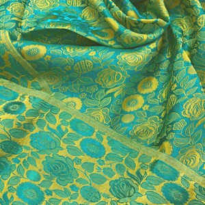 May include: A teal fabric with a yellow floral pattern. The fabric is folded and has a textured surface.
