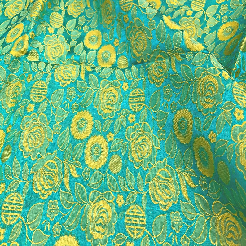 May include: A turquoise fabric with a repeating pattern of yellow roses, leaves, and small flowers.