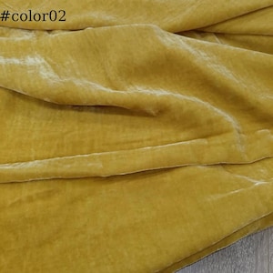 Puede incluir: Primer plano de una tela de terciopelo suave de color amarillo dorado. La tela est&aacute; doblada y drapeada, mostrando su textura y brillo.