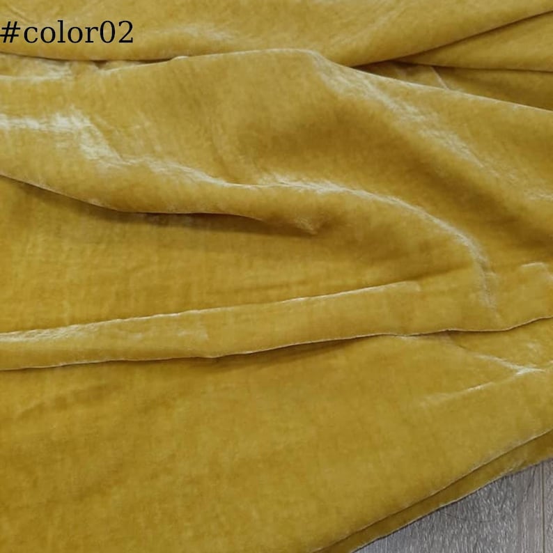 Puede incluir: Primer plano de una tela de terciopelo suave de color amarillo dorado. La tela est&aacute; doblada y drapeada, mostrando su textura y brillo.