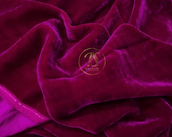 Könnte beinhalten: Nahaufnahme eines tiefvioletten Samtstoffes mit einem dezenten Glanz. Der Stoff ist drapiert und gefaltet, wodurch weiche, fließende Linien entstehen. Der Stoff ist texturiert und luxuriös.