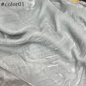 May include: A close-up of a light grey fabric with a soft, velvety texture. The fabric is wrinkled and has a subtle sheen.