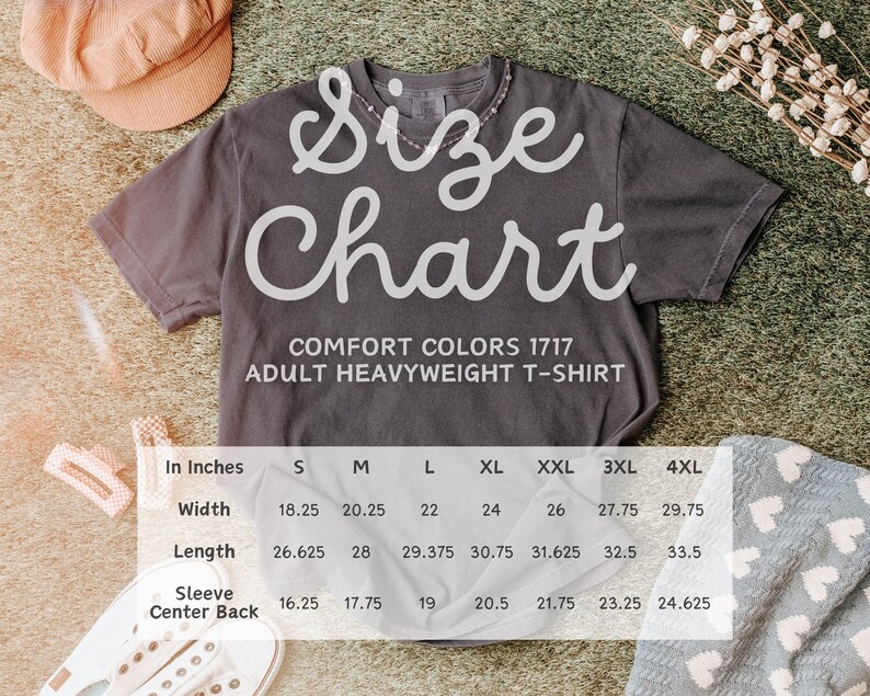 Pu&ograve; includere: Una maglietta grigio scuro Comfort Colors per adulti con una tabella delle taglie sovrapposta. La tabella mostra le misure in pollici per larghezza, lunghezza e centro manica posteriore per le taglie S-4XL. La maglietta &egrave; su una superficie strutturata.