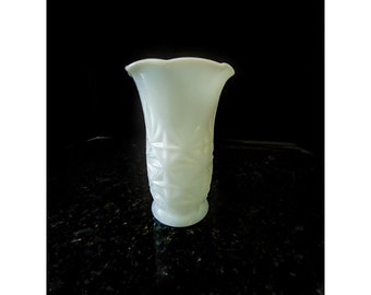 Op de afbeelding: Een witte melkglasvaas met een geometrisch patroon. De vaas heeft een gegolfde rand en een ronde basis.