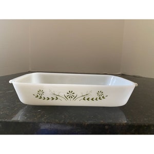 May include: White rectangular baking dish with green floral design. The dish has two handles on the sides.