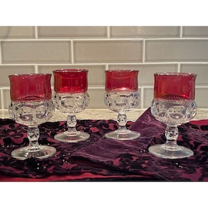 May include: Set of four clear glass stemmed goblets with a ruby red coloured rim. The goblets have a textured, bubbled design.