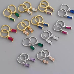 May include: Assortment of gold and silver hoop earrings with dangling rectangular gemstones in various colours, including green, blue, red, purple, and orange.