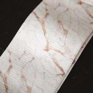 May include: White fabric ribbon with a brown marble pattern.