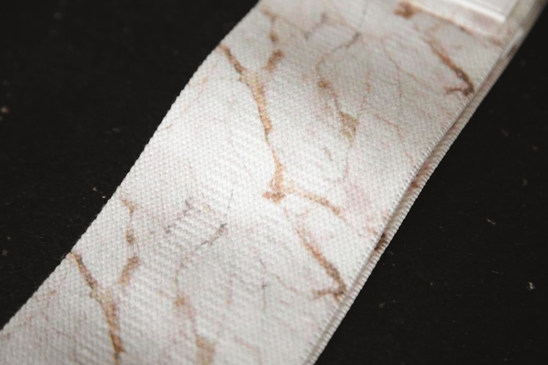 May include: White fabric ribbon with a brown marble pattern.