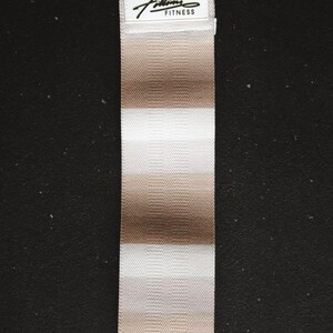 May include: A white and beige striped fabric resistance band with the text "Fitlife Fitness" on a white label.