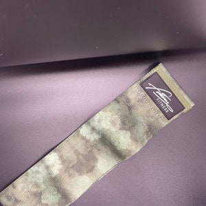May include: A green and brown camouflage exercise band with the text "Julianna Fitness" printed on the band.